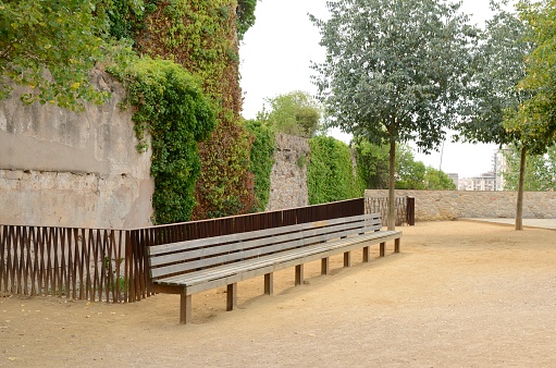 Long wooden bench in green space of Girona,  Catalonia, northeastern Spain.