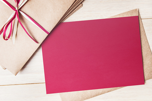 Mock up of red card with envelopes pile on wooden table