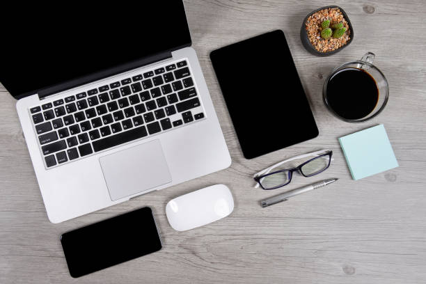 istock Office table with laptop computer, digital tablet, pen, smartphone, mouse, eyeglasses and coffee on white wood background. Desktop office mockup concept. 865388732