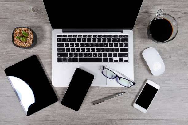 istock Office table with laptop computer, digital tablet, pen, smartphone, mouse, eyeglasses and coffee on white wood background. Desktop office mockup concept. 865388834