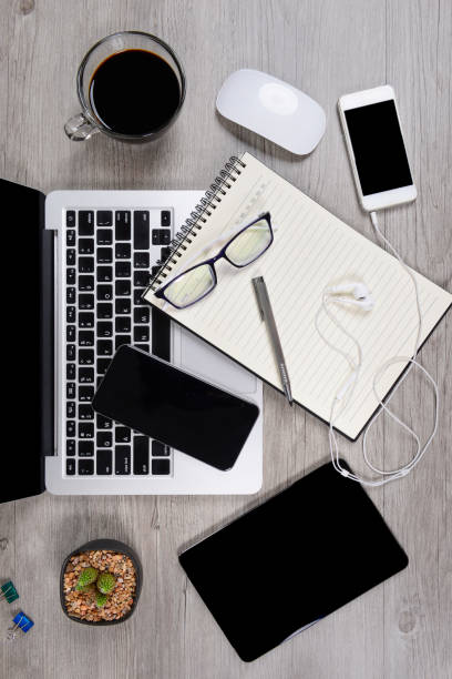 istock Office table with laptop computer, notebook, digital tablet, pen, smartphone, mouse, eyeglasses and coffee on white wood background. Desktop office mockup concept. 865388886