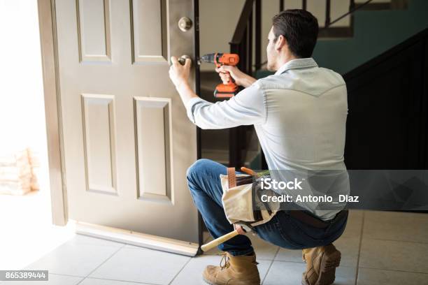 Young Man Fixing A Door Lock Stock Photo - Download Image Now - Door, Repairing, Installing