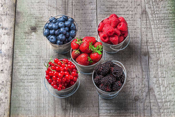 istock Berries colorful mix overhead in tin cans on wooden table 865389514
