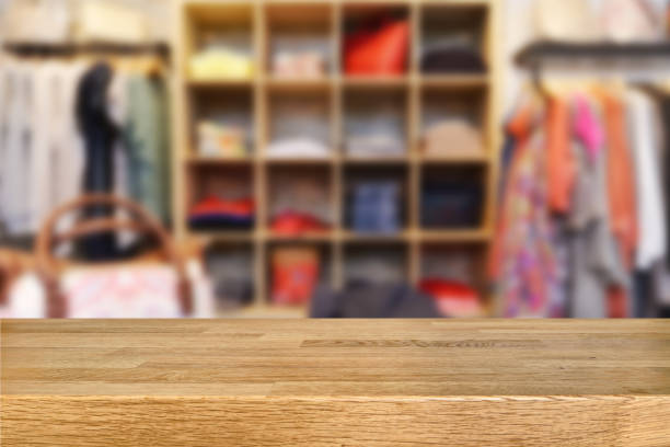 Wooden table and blurred retail display in a fashion store.