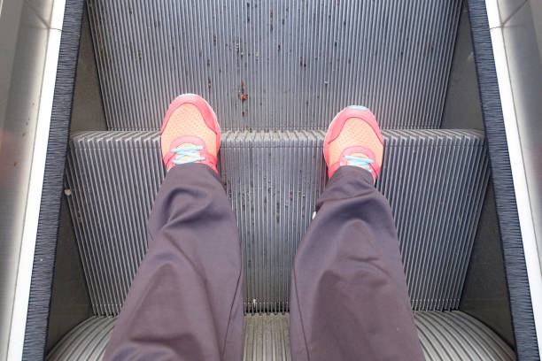 istock Feet in sneakers stand on escalator 865407352