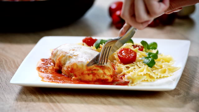 Italian food: chicken with tomato and pasta close-up. Girl eats