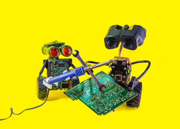 istock Two pretty cheerful robot repair printed circuit board with soldering iron 865427850