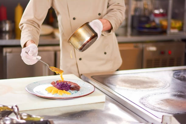 istock Chef pouring orange sauce on meat. 865429774