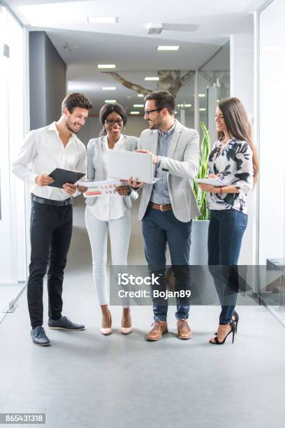 Gruppe Von Geschäftsleuten Über Projekt Auf Laptop Während Sie Im Büro Halle Stehen Stockfoto und mehr Bilder von Stehen