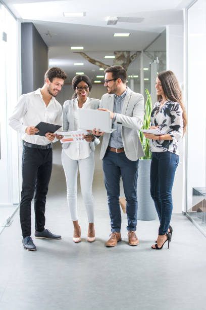 istock Group of business people discussing project on laptop while standing in office hall. 865431318