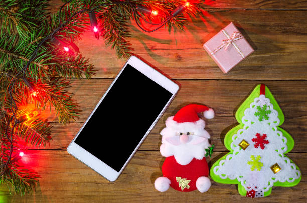 istock Christmas lights on a wooden background and smartphone, top view with copy space. 865435152