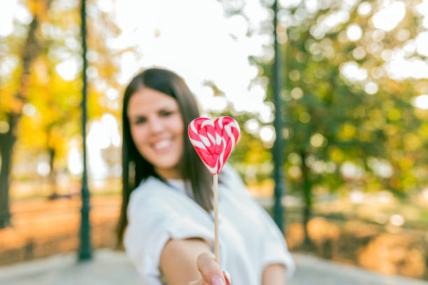 istock Young beautiful woman eating candy lollipops 865435390