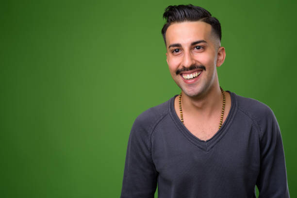 istock Young handsome Iranian man with mustache against green background 865438892
