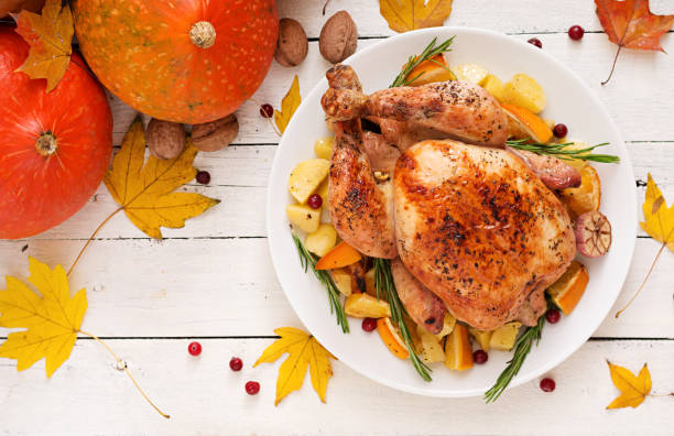 istock Roasted turkey garnished with cranberries on a rustic style table decorated with pumpkins, orange, apples and autumn leaf. Thanksgiving Day. Flat lay. Top view 865439358