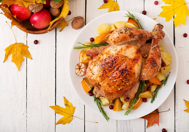 istock Roasted turkey garnished with cranberries on a rustic style table decorated with pumpkins, orange, apples and autumn leaf. Thanksgiving Day. Flat lay. Top view 865439382