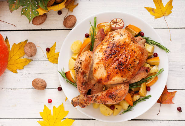 istock Roasted turkey garnished with cranberries on a rustic style table decorated with pumpkins, orange, apples and autumn leaf. Thanksgiving Day. Flat lay. Top view 865439444