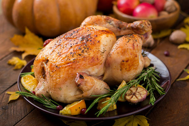 istock Roasted turkey garnished with cranberries on a rustic style table decorated with pumpkins, orange, apples and autumn leaf. Thanksgiving Day. 865442786