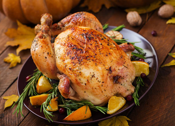 istock Roasted turkey garnished with cranberries on a rustic style table decorated with pumpkins, orange, apples and autumn leaf. Thanksgiving Day. 865442792