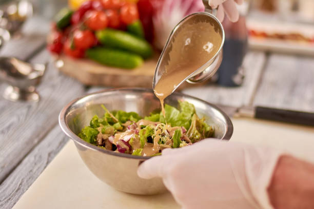 istock Chef pouring sauce on mixed salad. 865443140