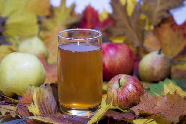 Fresh apple juice on table with apples and maple leaves. Autumn Abstraction