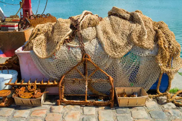 Commercial fishing gear including nets and scrapers on the dock at Honfleur, France.