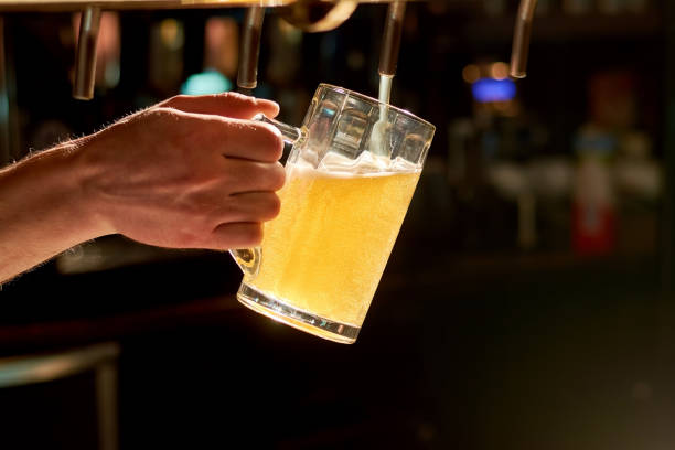 barkeeper hand strömenden lagerbier hautnah. - alcoholism assistance photography people stock-fotos und bilder