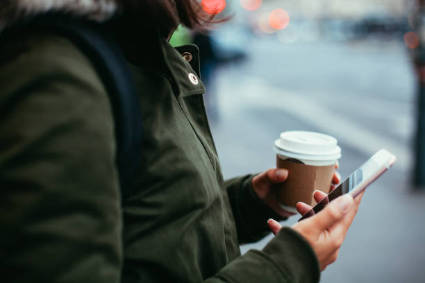istock Woman using smart phone and holding coffee 865464436