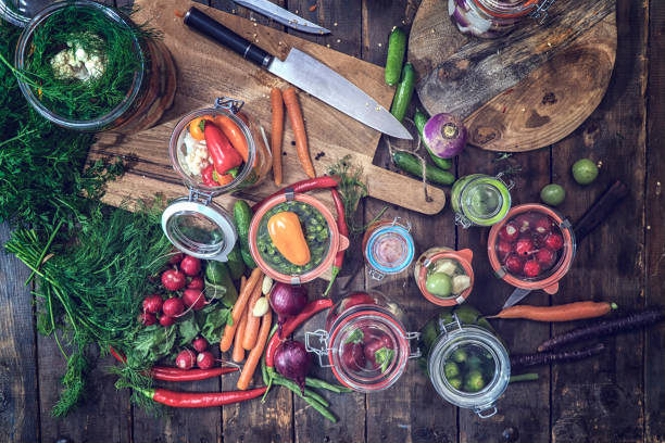 Preserving organic vegetables in jars like carrots, cucumbers, tomatoes, red onions and radishes.