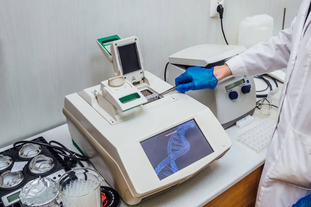 scientist with gloved hand putting dna sample into real-time pcr-cycler - pcr device imagens e fotografias de stock