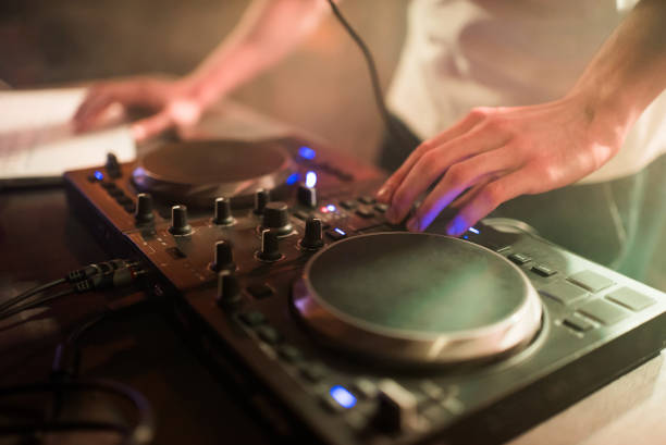 istock Hands of man DJ tweak various track controls on dj's deck at night club 865499360