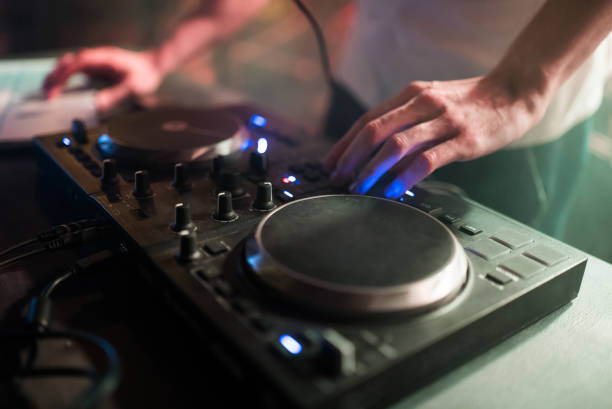 istock Hands of man DJ tweak various track controls on dj's deck at night club 865499372
