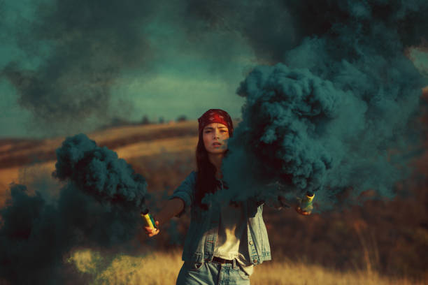 istock Young woman with smoke bombs in hands in a meadow 865505794