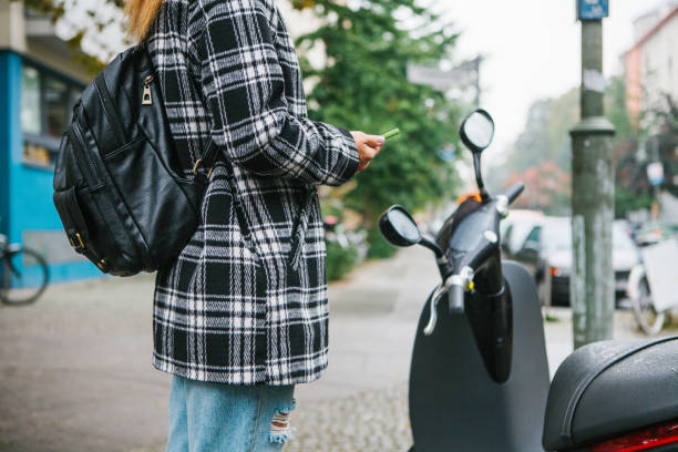 istock A tourist with a backpack is going to use an electric scooter through a mobile application in the phone and distally activate it. A popular vehicle in Berlin and Paris. 865515756
