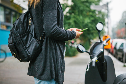 Un turista con una mochila se va a usar un scooter eléctrico a través de una aplicación móvil en el teléfono y activarlo distal. Un vehículo popular en Berlín y París. photo