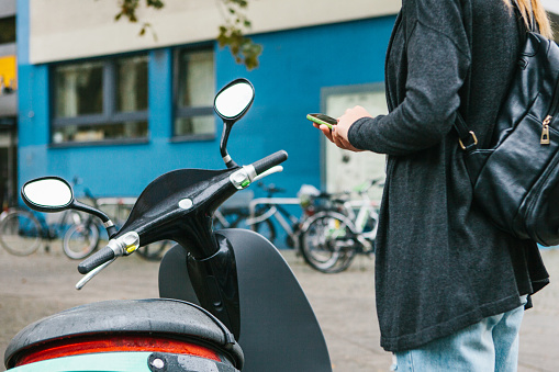 Un turista con una mochila se va a usar un scooter eléctrico a través de una aplicación móvil en el teléfono y activarlo distal. Un vehículo popular en Berlín y París. photo