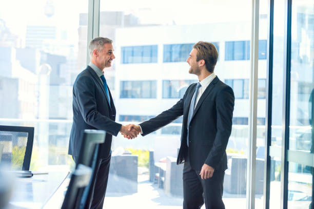 istock Mature and young businessmen shaking hands. 865527938