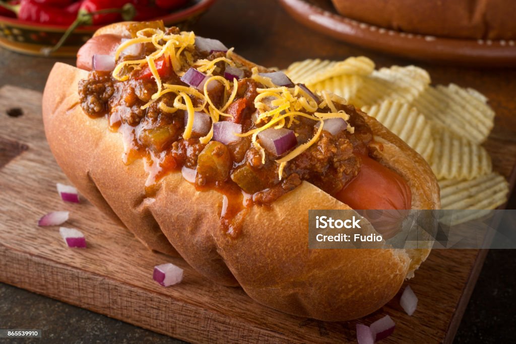 Chili Dog A delicious home made chili hot dog with red onion and cheddar cheese with potato chips. Hot Dog Stock Photo