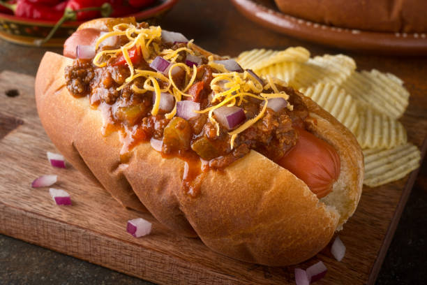 Chili Dog A delicious home made chili hot dog with red onion and cheddar cheese with potato chips. hotdog stock pictures, royalty-free photos & images