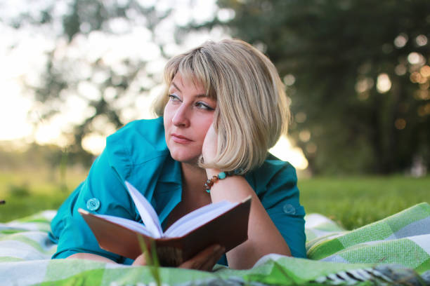 istock woman in park with book on grass 865540116