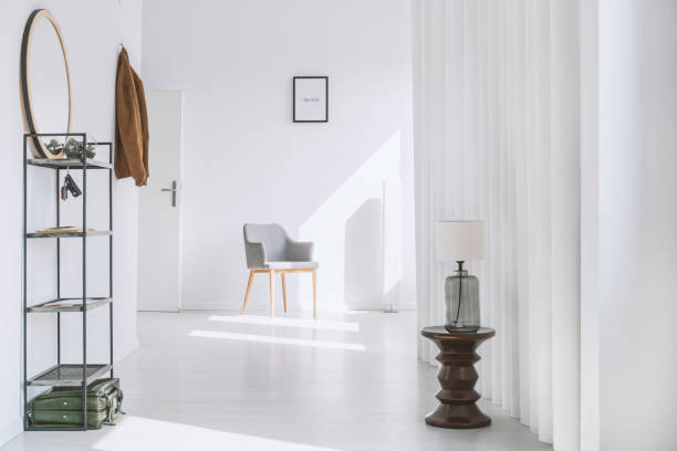 Hall in minimalist white apartment Simple hall with metal rack and gray armchair in minimalist white apartment key doormat stock pictures, royalty-free photos & images