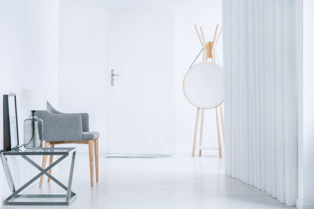 Round mirror and gray armchair Round mirror, simple gray armchair and modern table in bright hall interior key doormat stock pictures, royalty-free photos & images