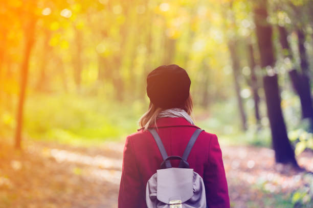 istock woman in red coat and backpack resting in autum park 865541632