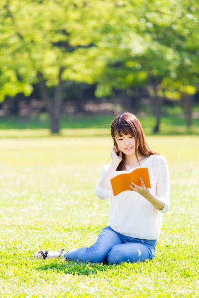 istock attractive asian woman reading book in park 865546006
