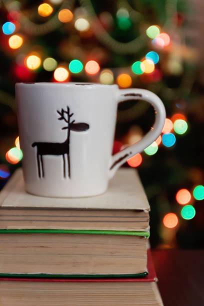 istock Christmas celebration with cup and gift box on books over bokeh and trees background 865548862