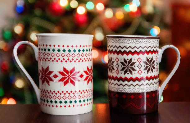 holidays, christmas, winter, food and drinks concept - close up of candy canes and cups on wooden table over lights stock photo