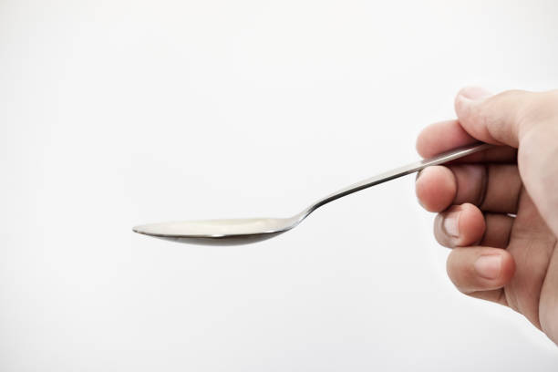 istock Close-up hand holding stainless spoon on white background 865549498
