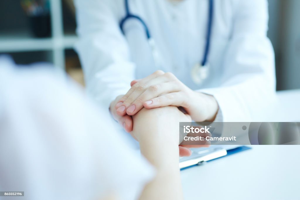 Friendly female doctor's hands holding female patient's hand for encouragement and empathy. Partnership trust and medical ethics concept. Patience Stock Photo