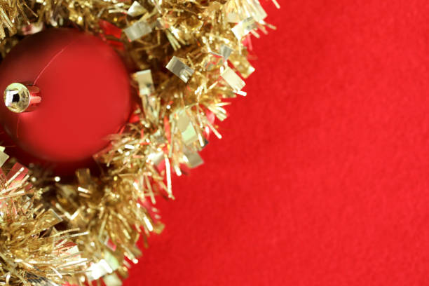 Holidays background of red Christmas ornaments on a red background with gold tinsel.  Copyspace.