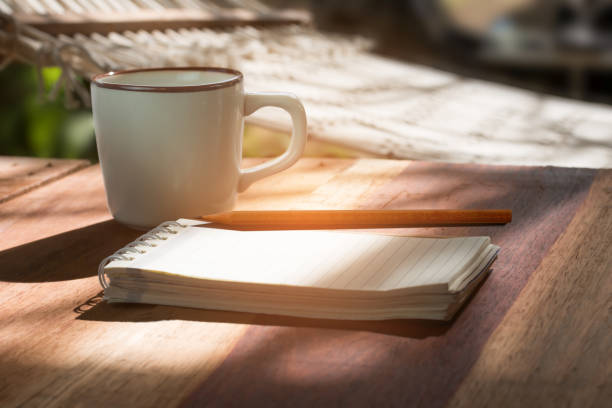 Open notebook with blank pages, pen and Cup of coffee on gray paving slab. Top view