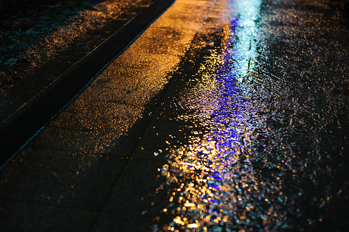 Colored light on wet asphalt in night city background